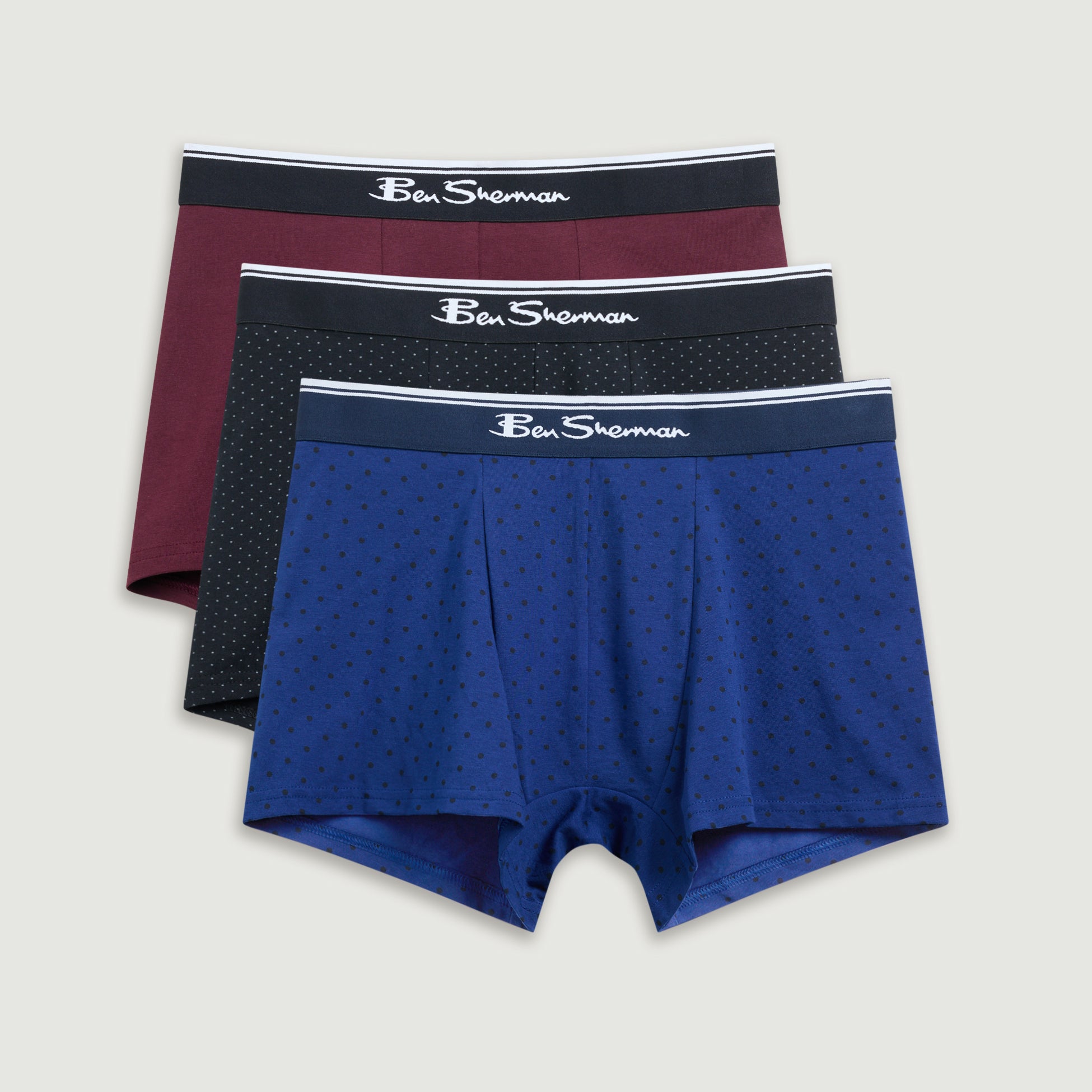 Three pairs of men's underwear with different colored waistbands on a light gray background.