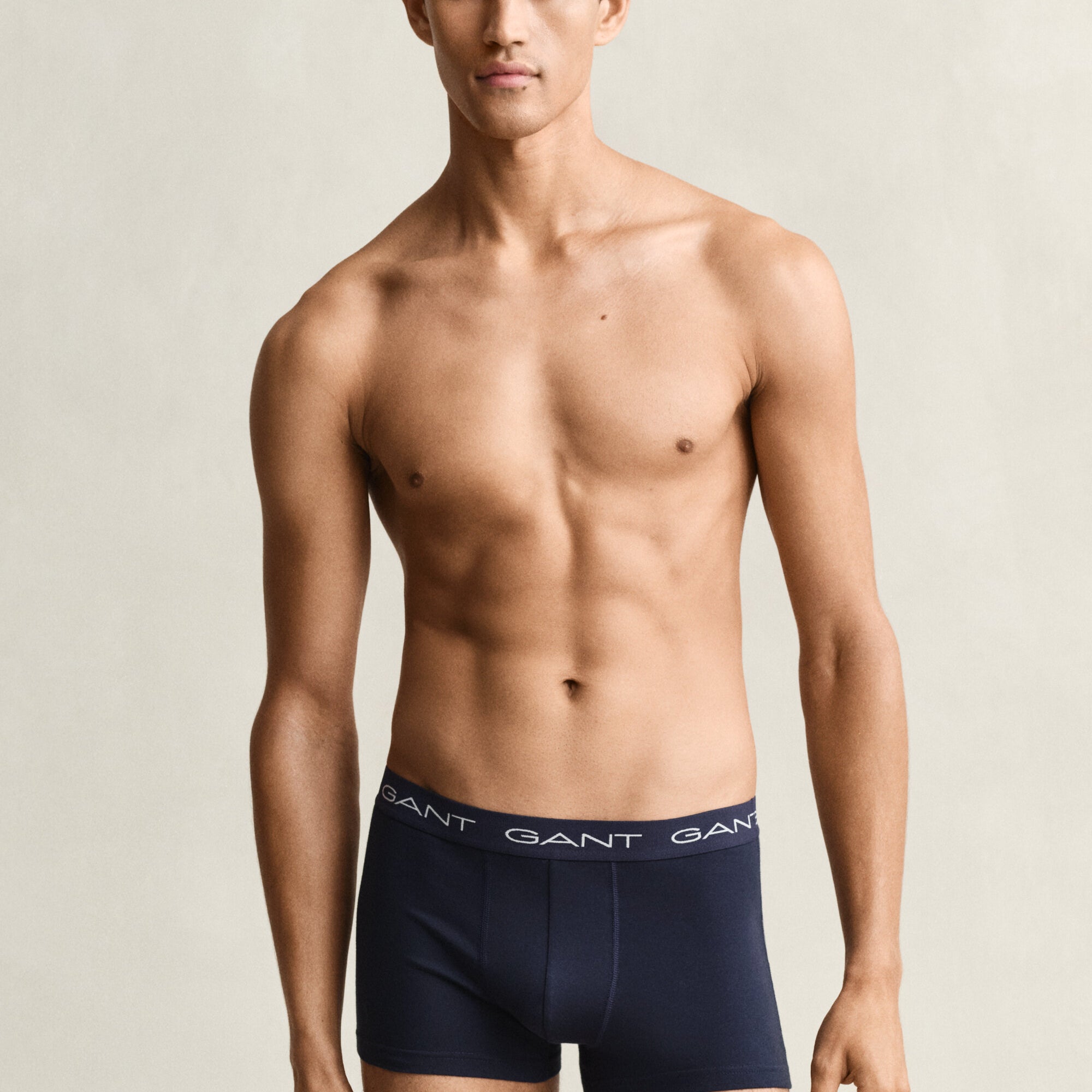 Man wearing navy GANT boxer briefs against a beige background