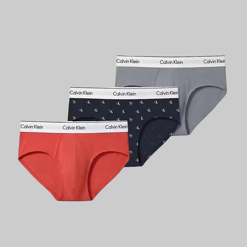 Three pairs of Calvin Klein underwear in red, navy, and gray on a white background.