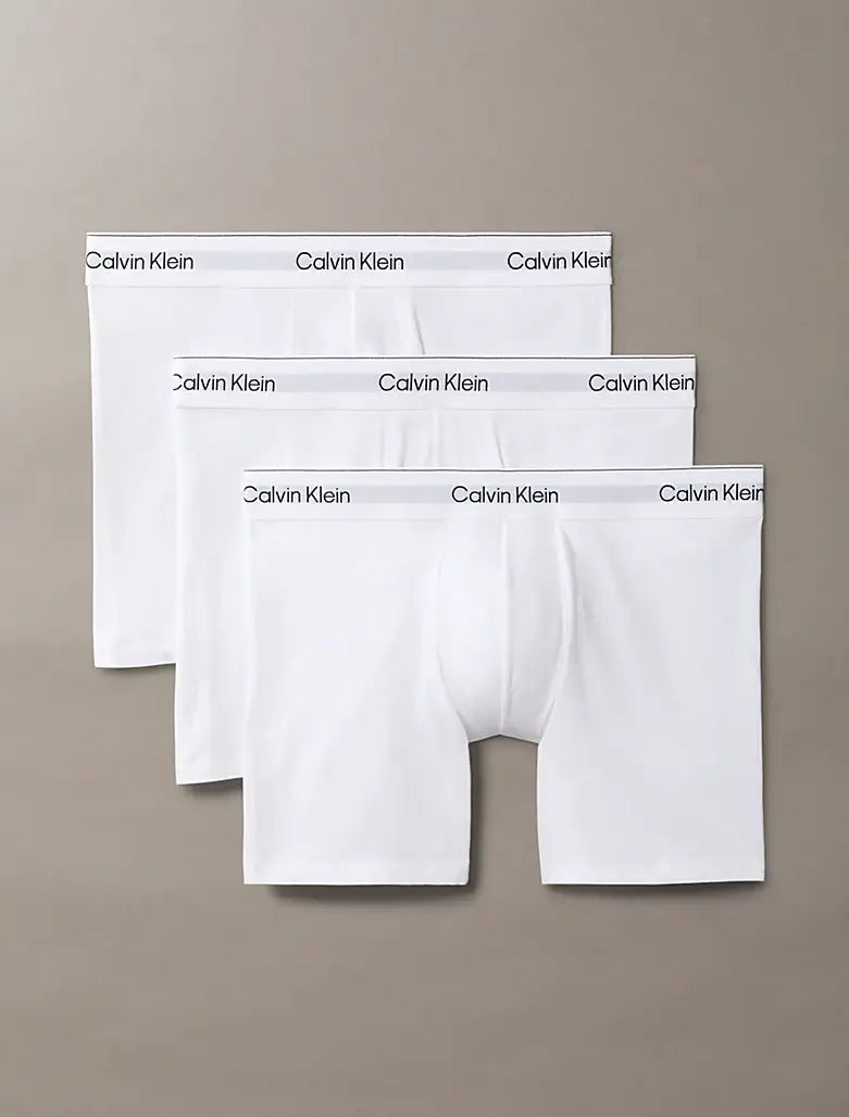 Three pairs of Calvin Klein white boxer briefs on a beige background