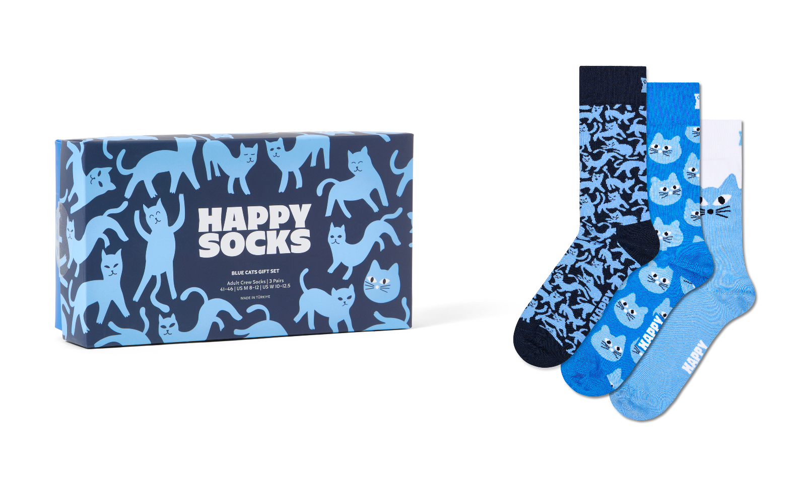 A boxed set of three patterned socks displayed beside the retail box on a light gray background. The packaging and sock designs feature blue cat illustrations and the text 'HAPPY SOCKS'.