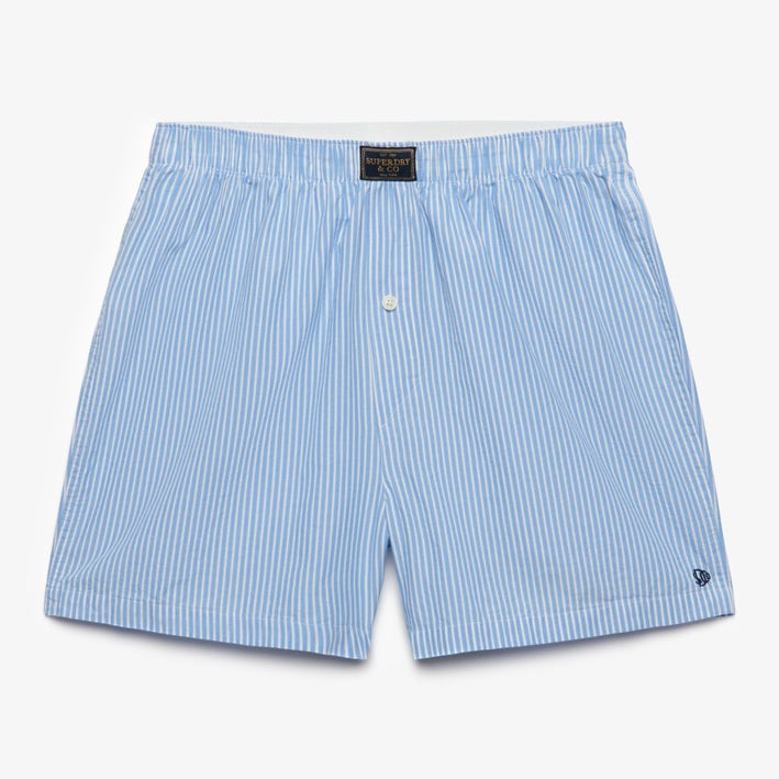 Light blue and white vertically striped boxer shorts with a small white embroidered logo on the lower left hem, displayed flat against a clean white background.