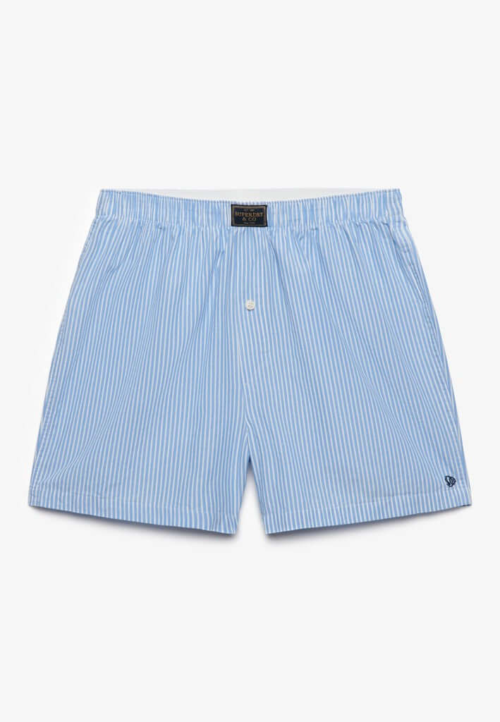Light blue and white vertically striped boxer shorts with a small white embroidered logo on the lower left hem, displayed flat against a clean white background.