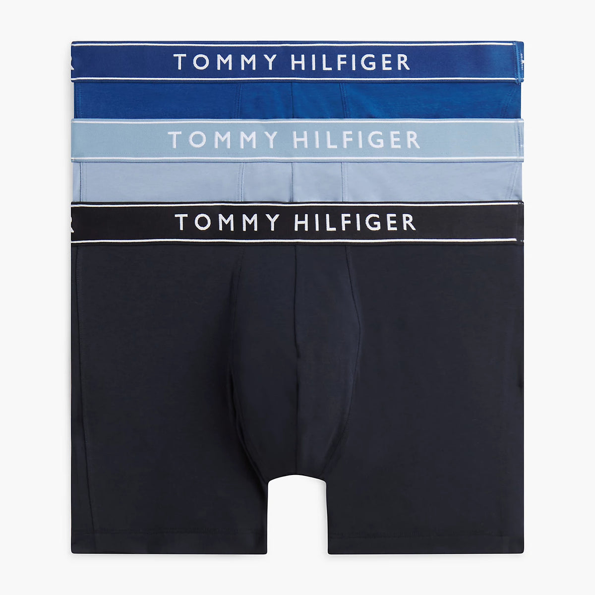 Three pairs of Tommy Hilfiger men's boxer briefs stacked vertically on a light gray background. The top pair is dark blue with white text, the middle pair is light blue with white text, and the bottom pair is black with white text.