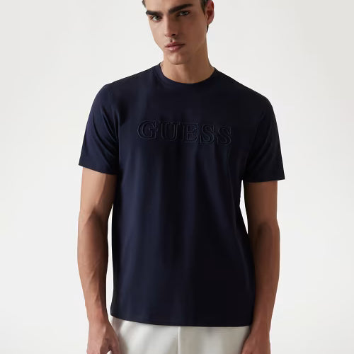 Man wearing a navy blue Guess t-shirt on a white background
