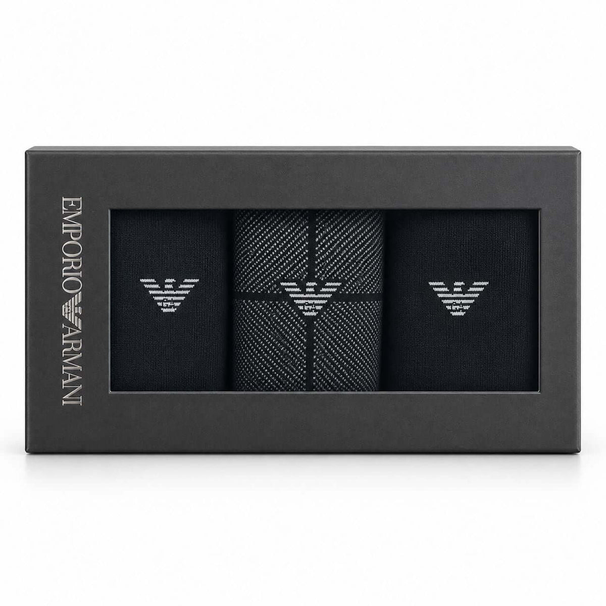 Emporio Armani 3-pack gift box containing black dress socks with silver embroidered eagle logos, shown in its black packaging on a white background.