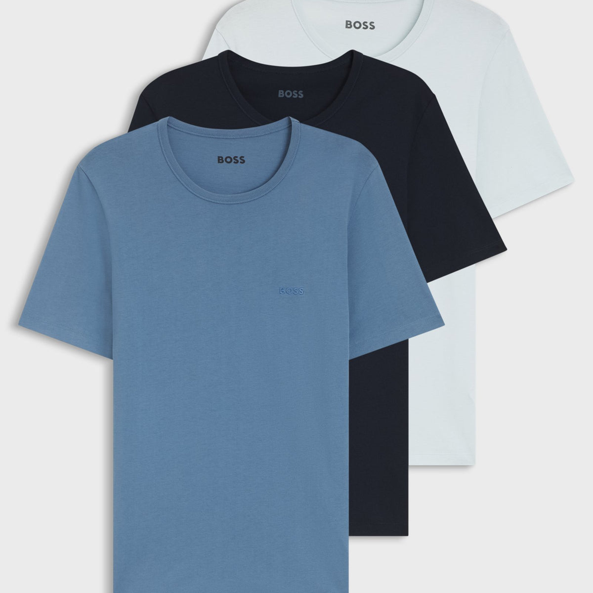 Three short-sleeve crewneck t-shirts stacked together, showing light blue, black, and white color options against a plain white background.