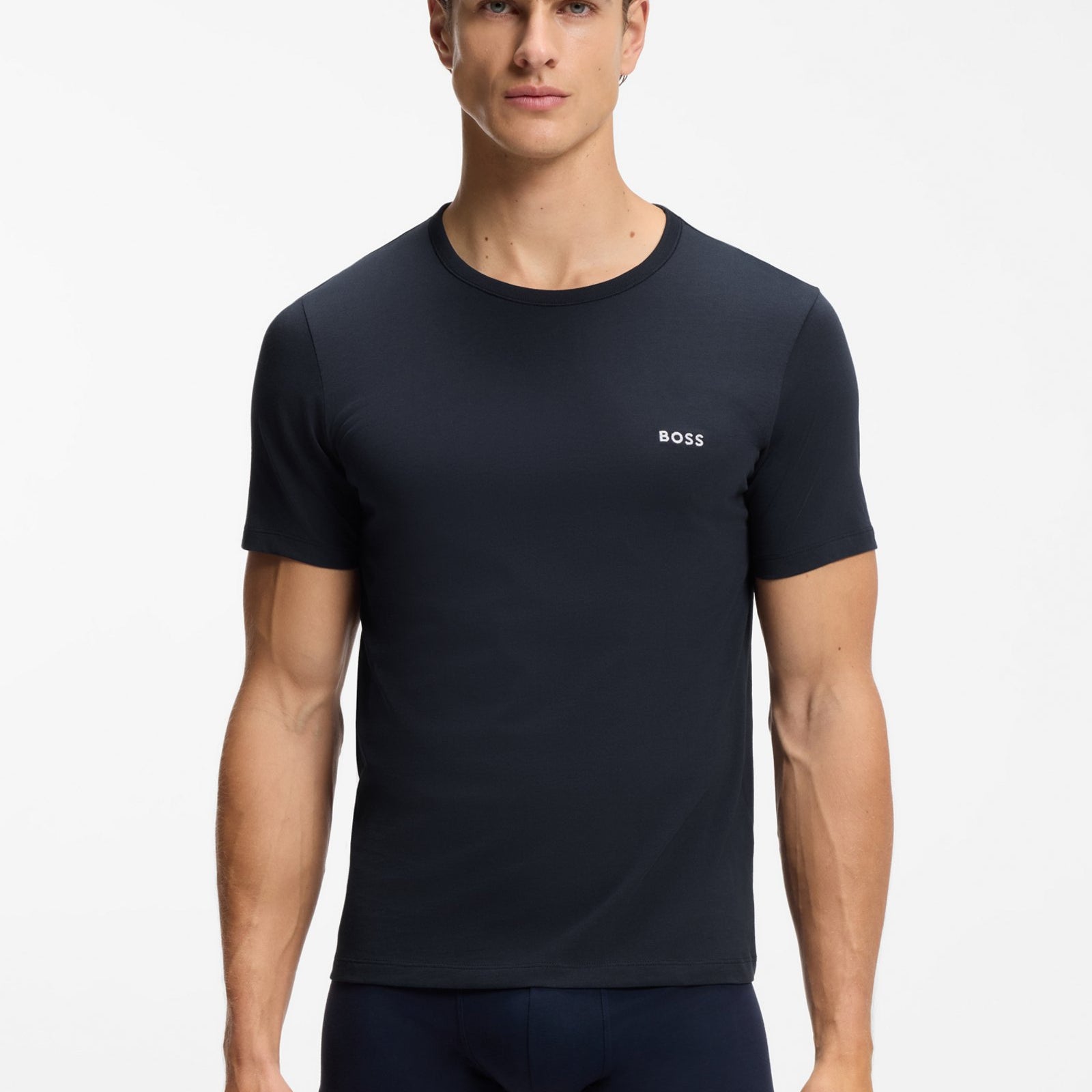 A male model wearing a dark navy blue short-sleeve crewneck t-shirt with a small white BOSS logo on the left chest, paired with matching navy boxer briefs, against a plain white studio background.