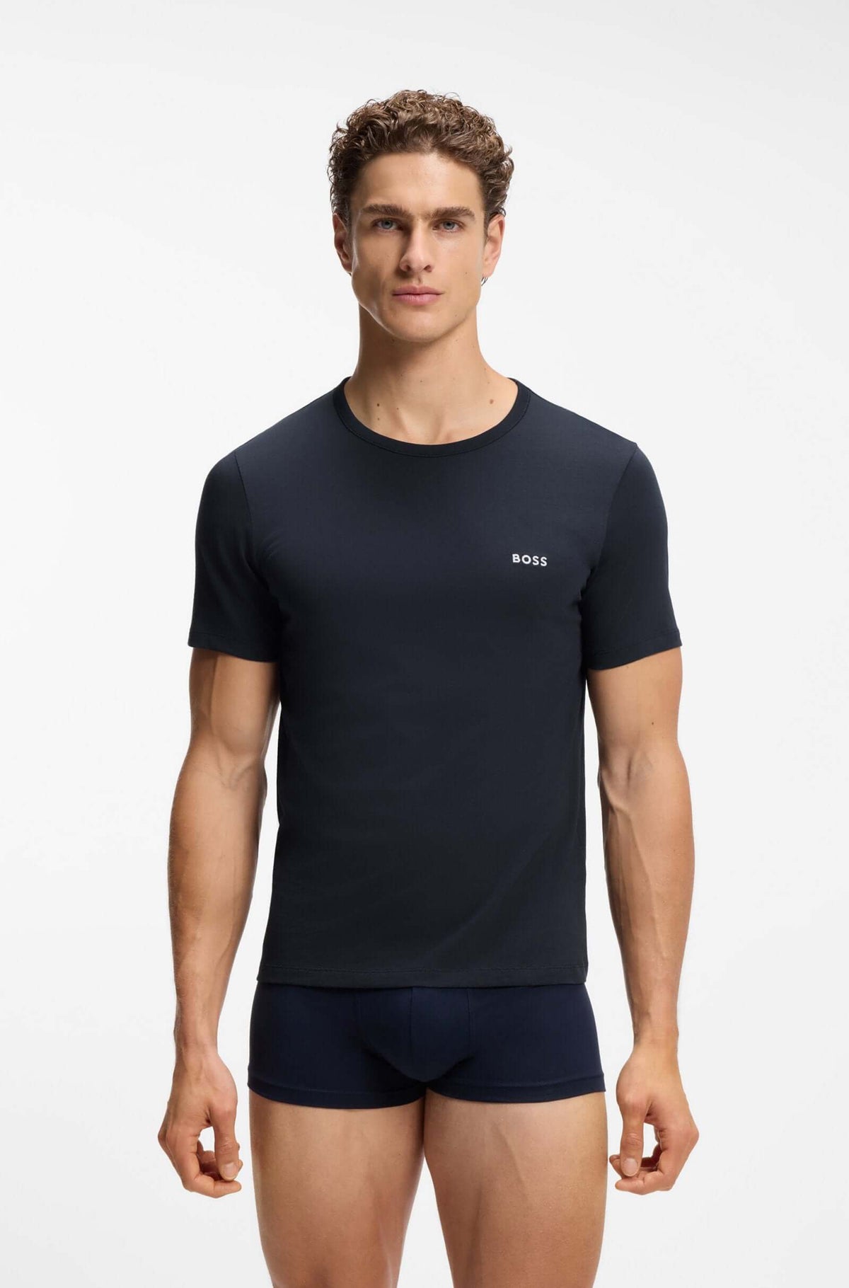 A male model wearing a dark navy blue short-sleeve crewneck t-shirt with a small white BOSS logo on the left chest, paired with matching navy boxer briefs, against a plain white studio background.