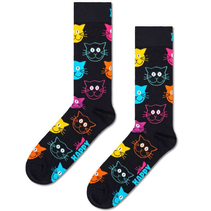 A pair of black crew socks with a colorful pattern of cartoon cat faces in yellow, pink, blue, orange, and purple, with the word 'HAPPY' printed in white near the foot.