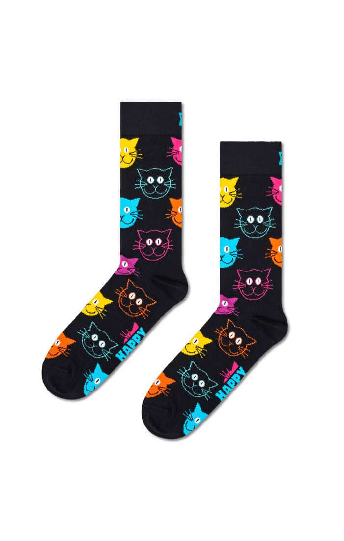 A pair of black crew socks with a colorful pattern of cartoon cat faces in yellow, pink, blue, orange, and purple, with the word 'HAPPY' printed in white near the foot.