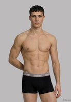 Man wearing black Calvin Klein underwear against a gray background
