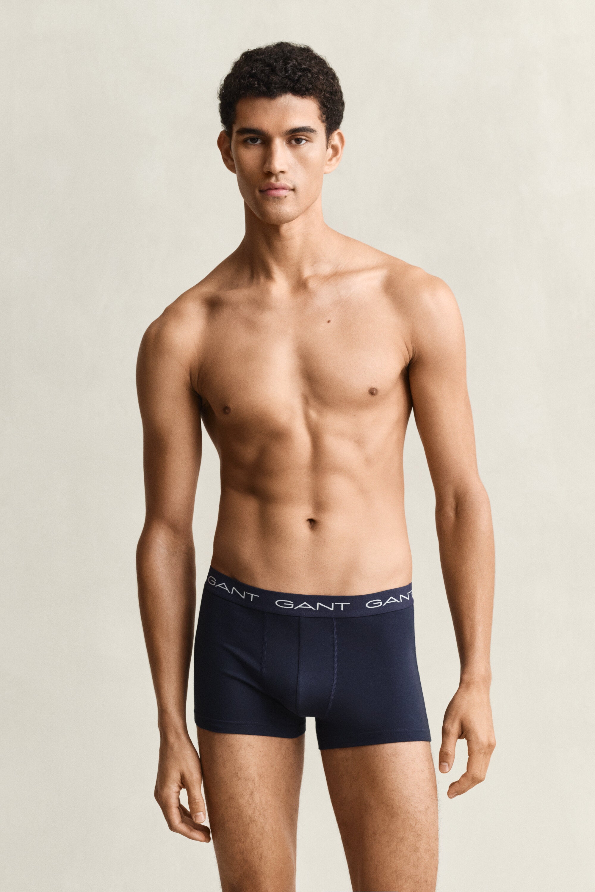 Man wearing navy GANT boxer briefs against a beige background