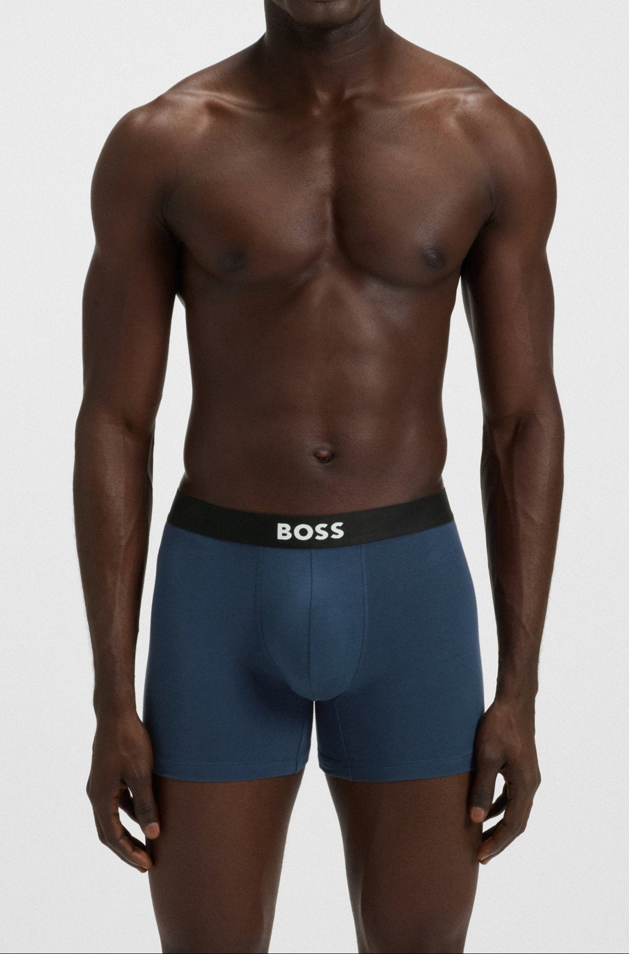 Man wearing blue underwear with a visible brand logo on a white background