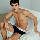 Man wearing Lacoste underwear sitting on a bed