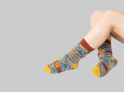 Colorful patterned socks worn by a person on a black background