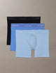 Three pairs of Calvin Klein boxer briefs in black, blue, and light blue on a beige background.