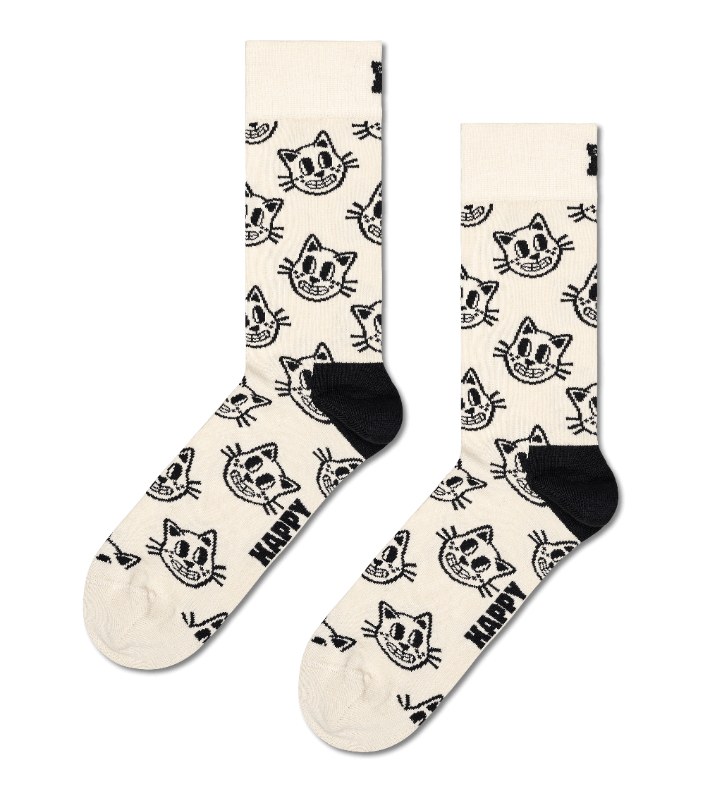 A pair of crew socks in cream with a black cartoon cat face pattern and the word 'HAPPY' printed near the foot, shown on a plain white background.