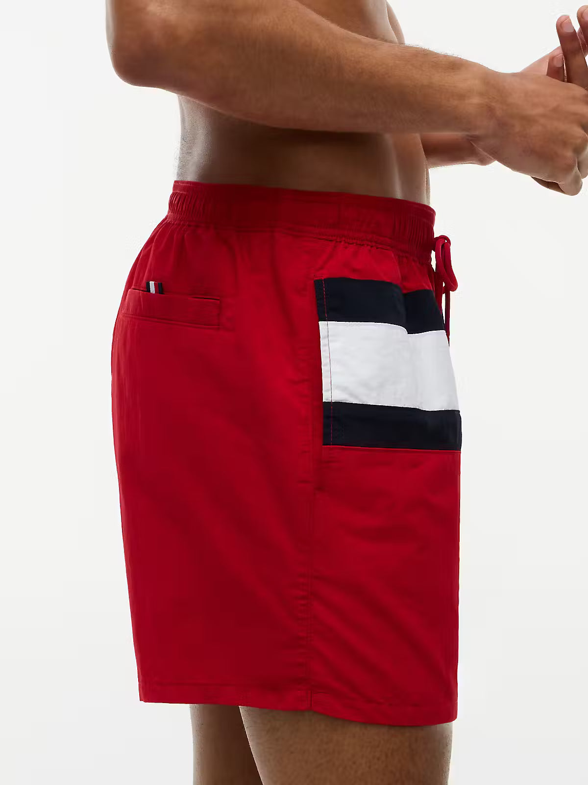 Red swim trunks with a navy and white striped pocket detail, shown on a model against a white background.