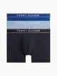 Three pairs of Tommy Hilfiger men's boxer briefs stacked vertically on a light gray background. The top pair is dark blue with white text, the middle pair is light blue with white text, and the bottom pair is black with white text.