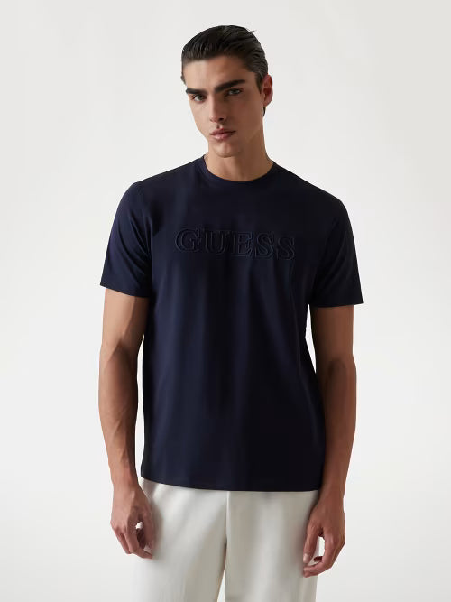 Man wearing a navy blue Guess t-shirt on a white background