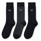 Three crew-length socks displayed side by side on a plain white background. Two socks are solid black with a small silver embroidered logo near the cuff, and one sock is black with a subtle gray herringbone pattern and a matching silver logo.