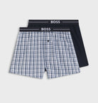 Two pairs of boxer shorts with a checkered pattern and black waistband on a white background, branded 'BOSS'.