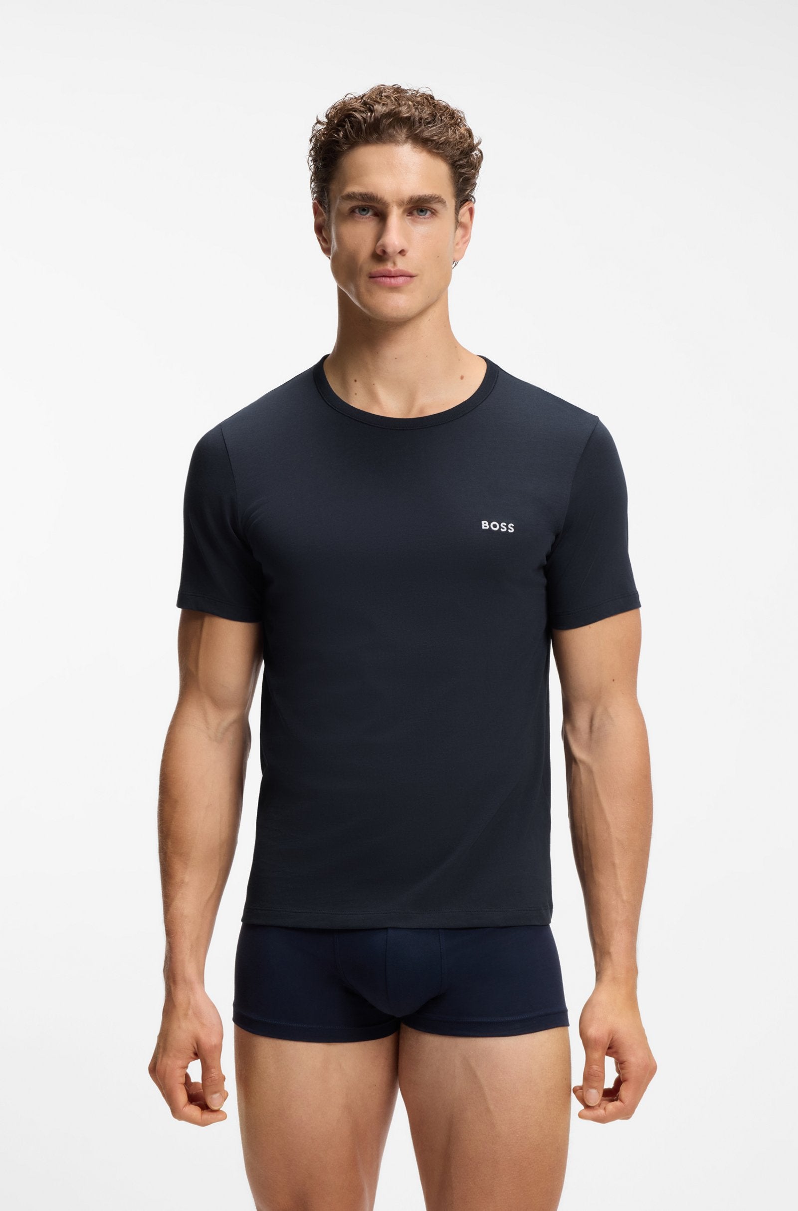 A male model wearing a dark navy blue short-sleeve crewneck t-shirt with a small white BOSS logo on the left chest, paired with matching navy boxer briefs, against a plain white studio background.